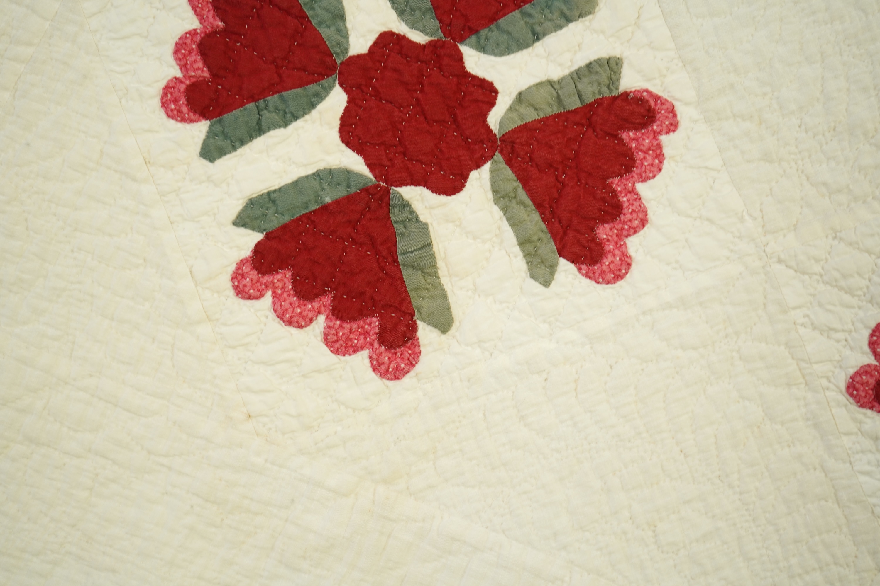 An American quilt from Kentucky, circa 1900. Intricately hand quilted on a white ground, appliquéd with stylistic repeating floral motifs in strong red and green cottons, all hand pieced. This quilt is a fine example of